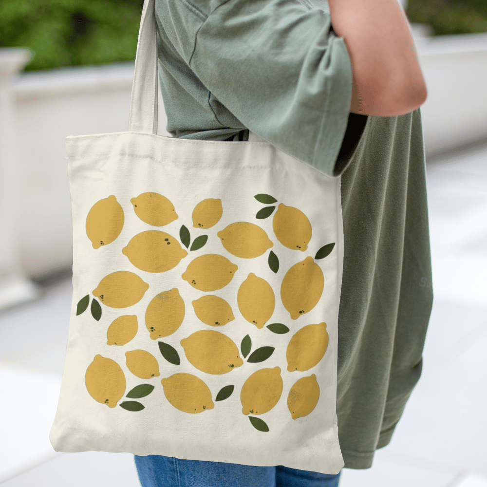 Organic cotton tote bag with a yellow lemon and green leaf all-over print design, reusable and eco-friendly.