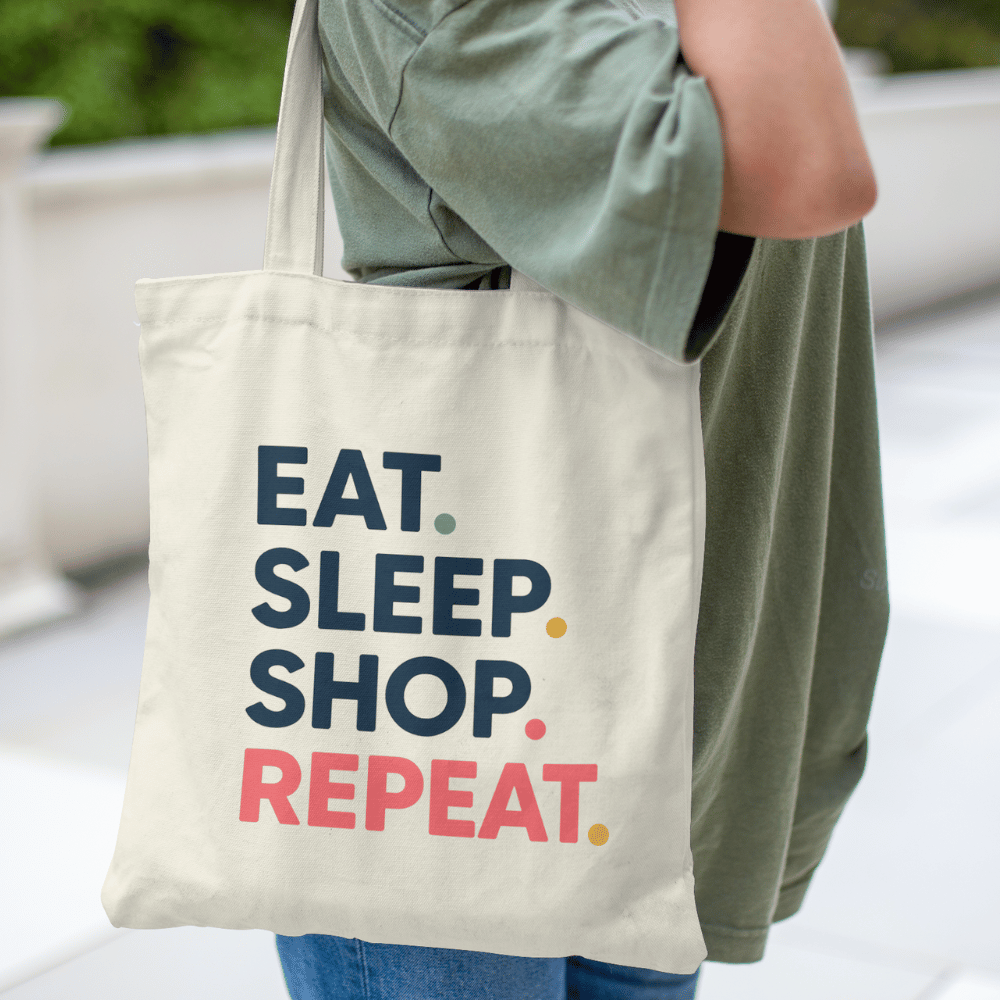 Tote bag with the quote “Eat. Sleep. Shop. Repeat.” in bold colourful text – reusable cotton canvas bag