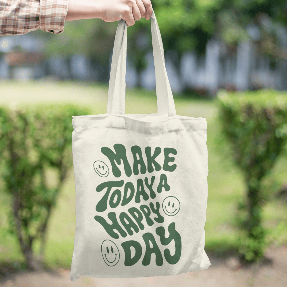 Organic cotton tote bag with “Make Today a Happy Day” design, reusable and eco-friendly with long handles.