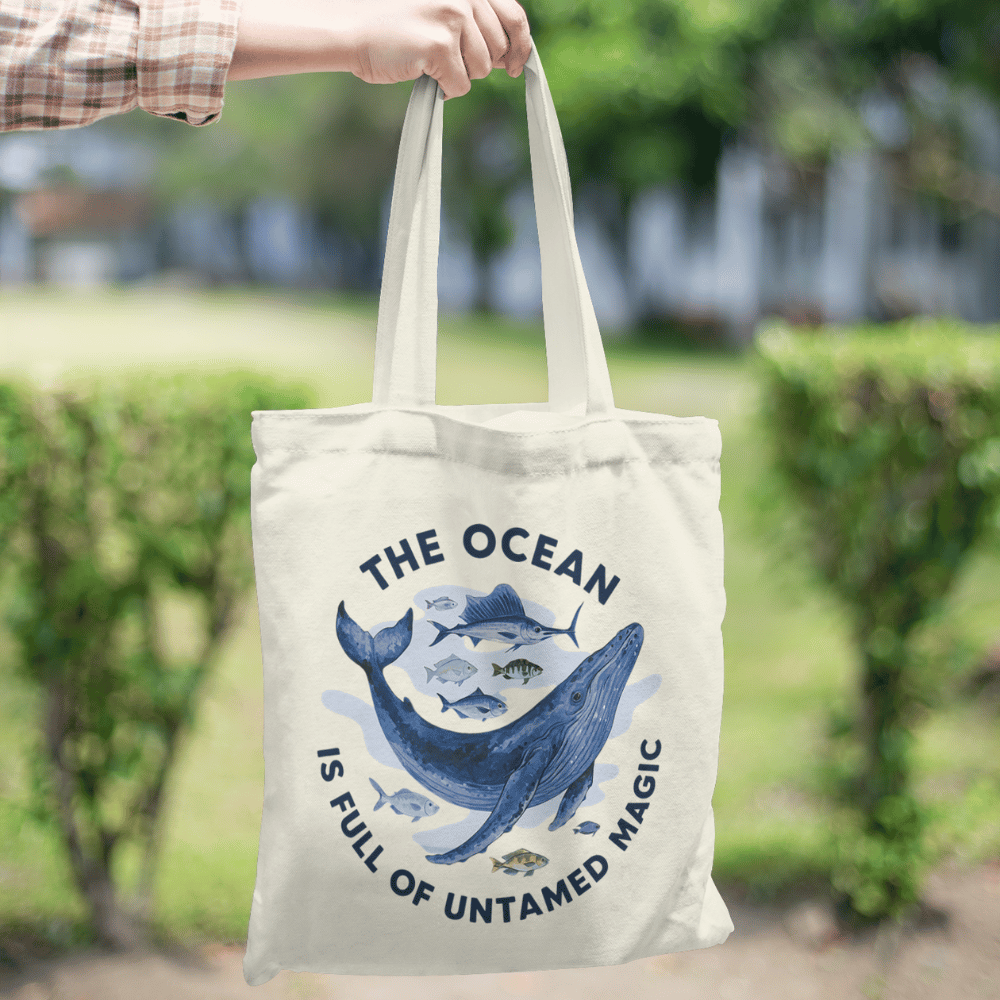Eco-friendly organic cotton tote bag with whale and fish ocean design and “The Ocean Is Full of Untamed Magic” quote.