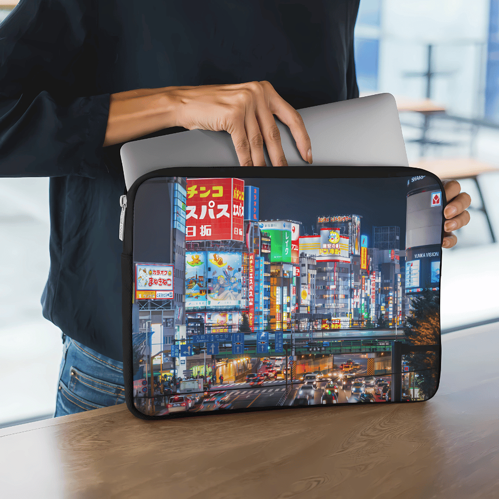 Person placing a laptop into a customisable white laptop sleeve with “Your Design Here” placeholder text in a modern workspace.