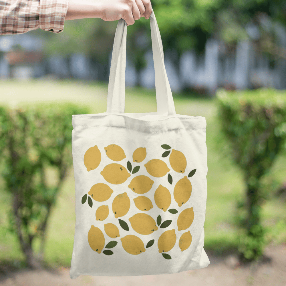 Organic cotton tote bag with a yellow lemon and green leaf all-over print design, reusable and eco-friendly.