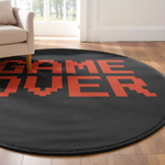 Round black rug with red pixel-style “GAME OVER” text, placed in a bright modern room with minimalist furnishings and warm neutral tones.